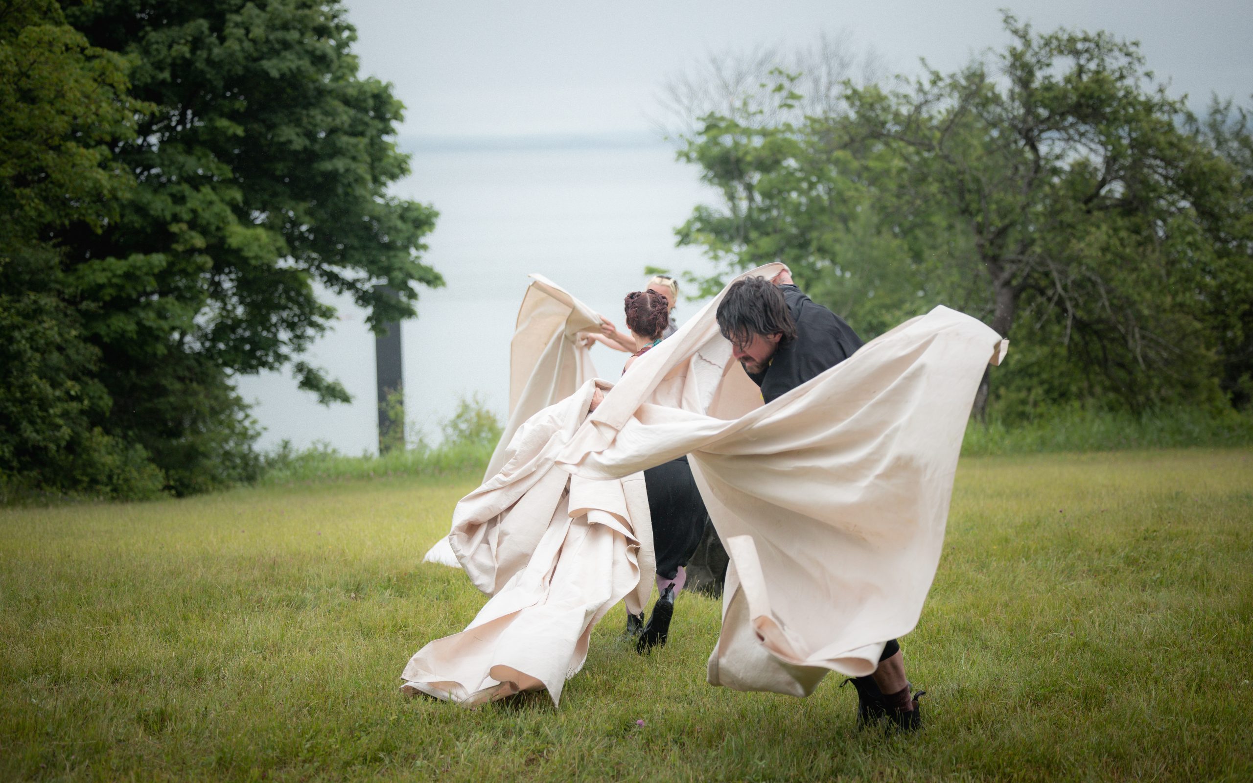 Deux interprètes avec des draps blancs devant le Fleuve.